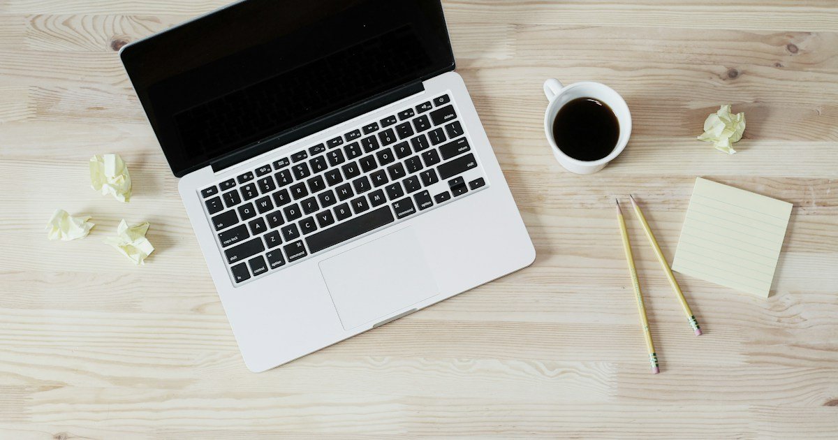 Desk with a laptop, notebook, pen and coffee for planning an email sequence