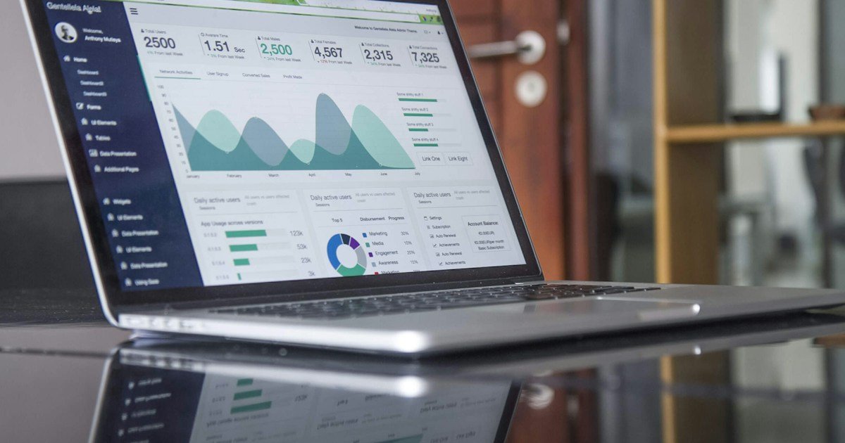 Laptop displaying analytics beside a notebook and phone