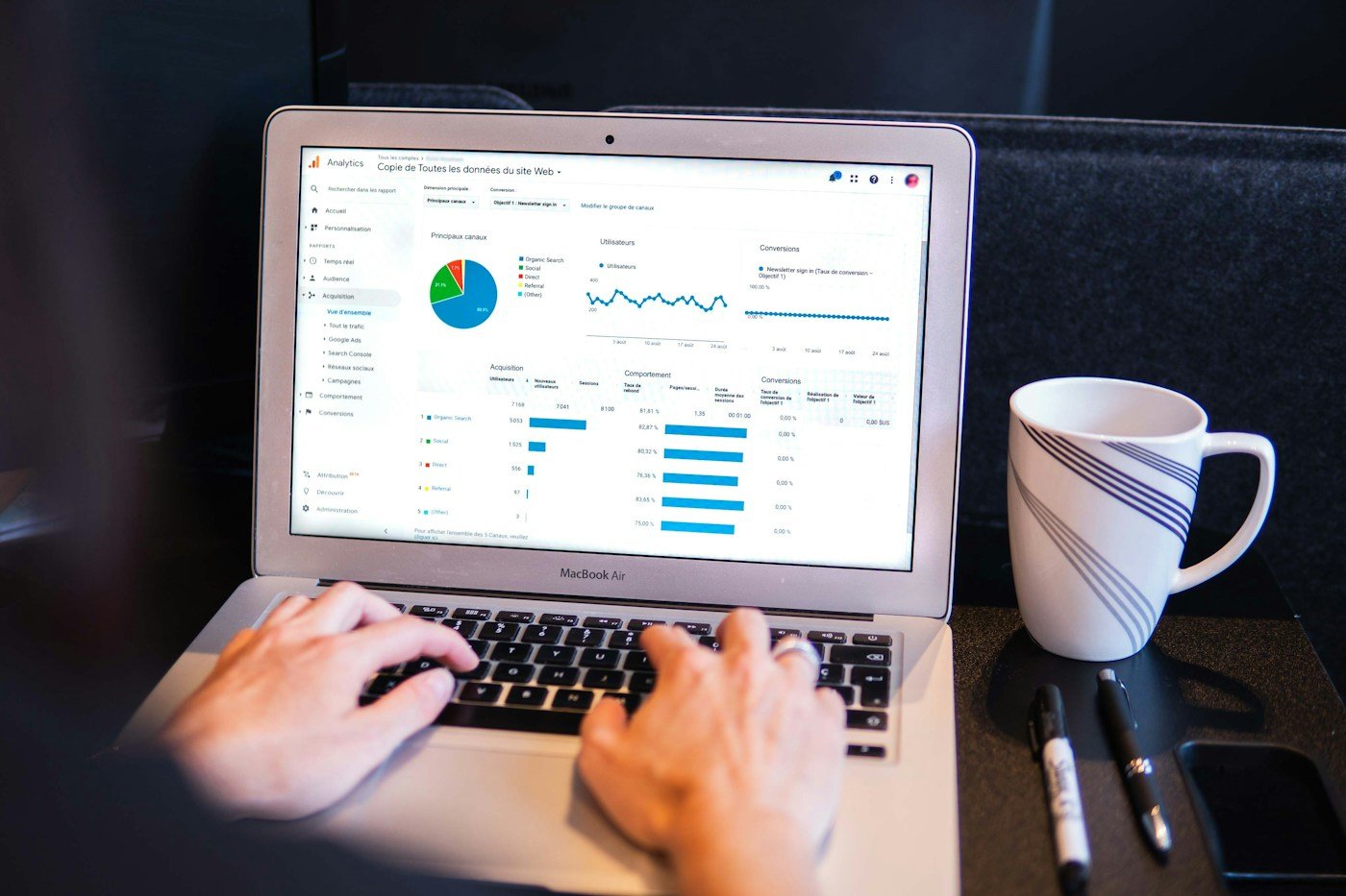 Laptop displaying analytics charts beside a notebook, illustrating an SEO content audit