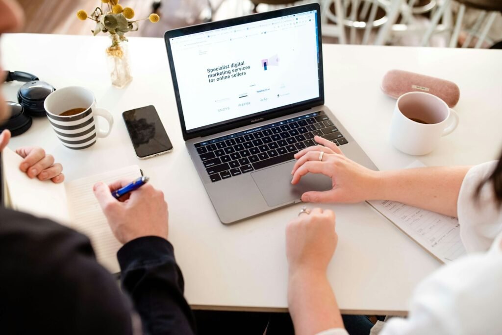 Two people working together at a laptop in a workspace